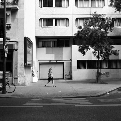 Black and white street photography of the french street photographer David Décamps representing a woman walking on the street in Paris.