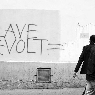 Black and white street photography of the french street photographer David Décamps representing two men with slave revolt written on the wall in Paris.