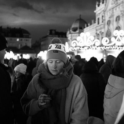 Black and white street photography of the french street photographer David Décamps representing a young woman with her eyes closed in a Christmas market in Vienna