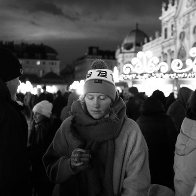 Black and white street photography of the french street photographer David Décamps representing a young woman with her eyes closed in a Christmas market in Vienna