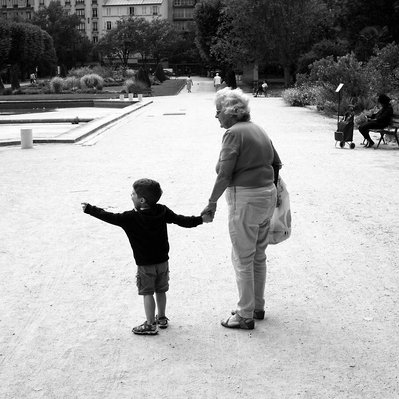 Black and white street photography of the french street photographer David Décamps representing a baby with his grandmother in a park in Paris.