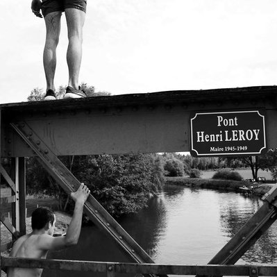 Black and white street photography of the french street photographer David Décamps representing two kids on a bridge in a small village of Erondelle, France.