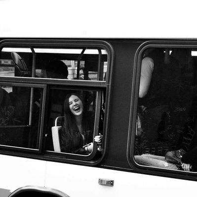 Black and white street photography of the french street photographer David Décamps representing a woman laughing out loud in a bus in Montreal.