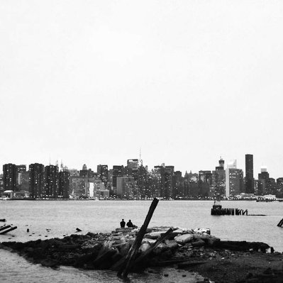 Black and white street photography of the french street photographer David Décamps representing two men in front of the skyline of New York City, USA.
