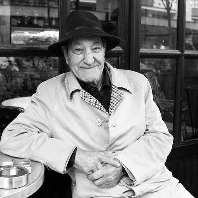 Black and white street photography of the french street photographer David Décamps representing a man with a malicious look drinking a coffee in Paris.
