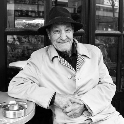 Black and white street photography of the french street photographer David Décamps representing a man with a malicious look drinking a coffee in Paris.