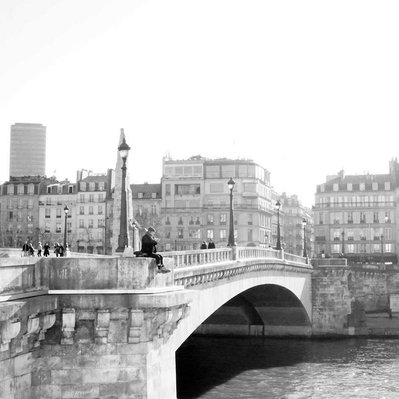 Black and white street photography of the french street photographer David Décamps representing a man sit on a bridge above the Seine river in Paris.