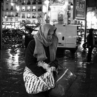 Black and white street photography of the french street photographer David Décamps representing a woman alone under the rain with a scarf on her head in Paris.