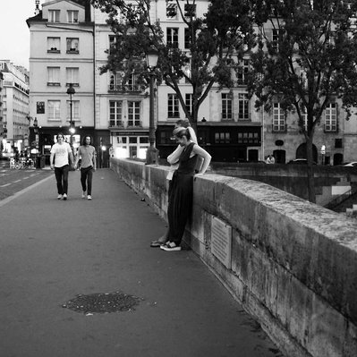 Black and white street photography of the french street photographer David Décamps representing a couple on a bridge in Paris during the summer in Paris.