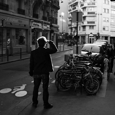 Black and white street photography of the french street photographer David Décamps representing the back of a man looking far away the sun in his eyes in Paris.