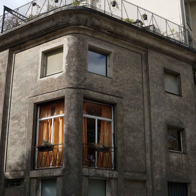 Street photography in colors of the french street photographer David Décamps representing a house in Paris with a orange curtain in the light.