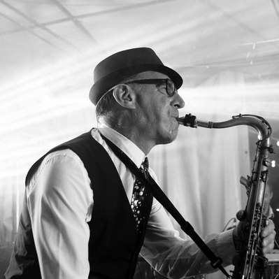 Black and white street photography of the french street photographer David Décamps representing the portrait of a man playing saxophone during a wedding.