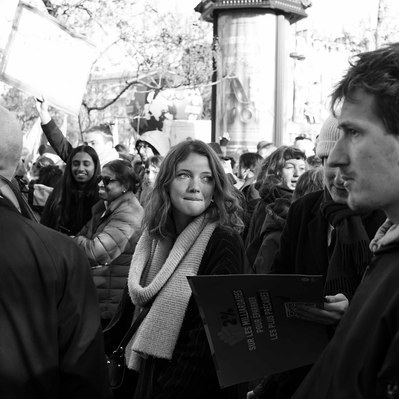Black and white street photography of the french street photographer David Décamps representing a young woman with a long scarf in a strike in Paris.