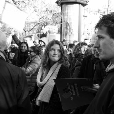 Black and white street photography of the french street photographer David Décamps representing a young woman with a long scarf in a strike in Paris.