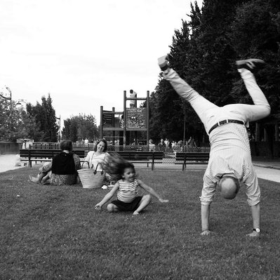 Black and white street photography of the french street photographer David Décamps representing a grand father wheeling up in a park with her grand daughter in Paris.