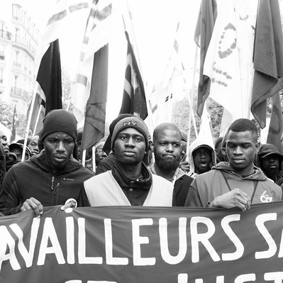 Black and white street photography of the french street photographer David Décamps representing some undocumented workers during a strike in Paris.
