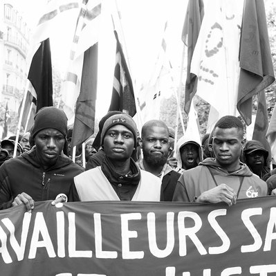 Black and white street photography of the french street photographer David Décamps representing some undocumented workers during a strike in Paris.