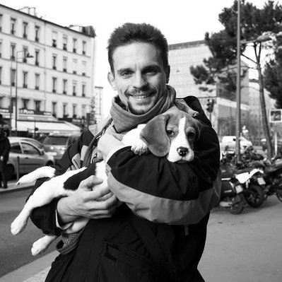Black and white street photography of the french street photographer David Décamps representing a man with a baby dog in his arms in Paris.