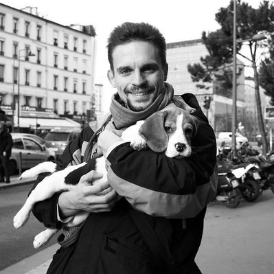 Black and white street photography of the french street photographer David Décamps representing a man with a baby dog in his arms in Paris.