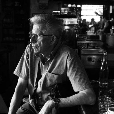Black and white street photography of the french street photographer David Décamps representing a man propping up in a bar in Paris.