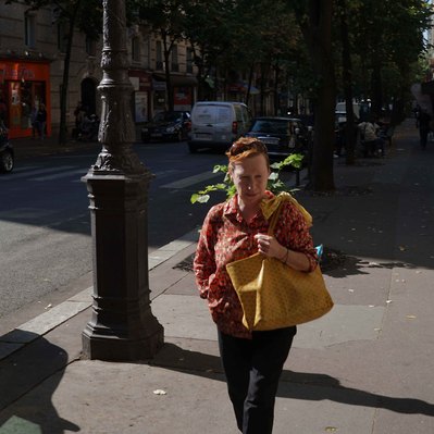 Street photography in colors of the french street photographer David Décamps representing a woman carrying some flowers in her back in Paris.