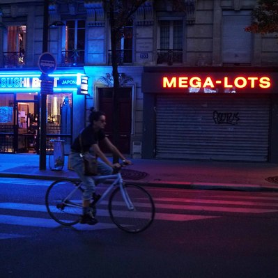 Street photography in colors of the french street photographer David Décamps representing a young woman on a bike during the night in Paris.