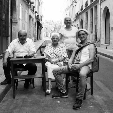 Black and white street photography of the french street photographer David Décamps representing a band of people taking a coffee in the middle of a road in Paris.