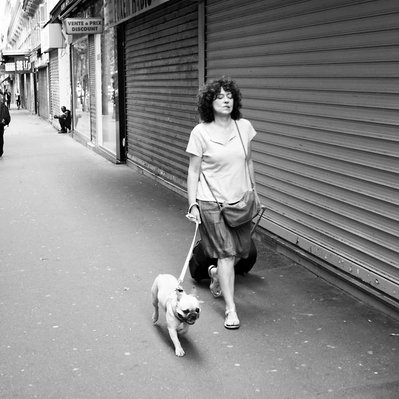 Black and white street photography of the french street photographer David Décamps representing a woman bitting her lips with her dog in Paris.