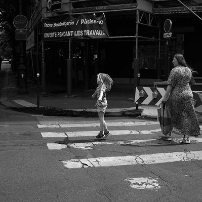 Black and white street photography of the french street photographer David Décamps representing a little girl doing jumps on the sidewalk in Paris.