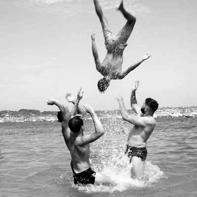 Black and white street photography of the french street photographer David Décamps representing a boy his head upside down during a jump in the water.