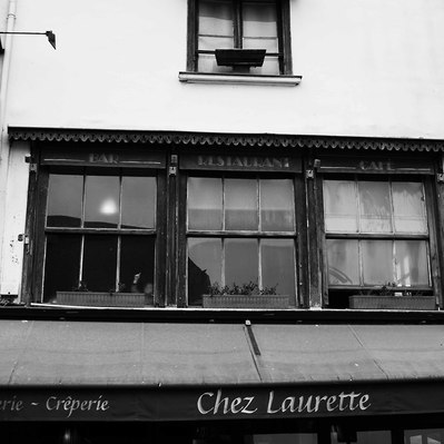 Black and white street photography of the french street photographer David Décamps representing a boy drawing something on a window in Honfleur.