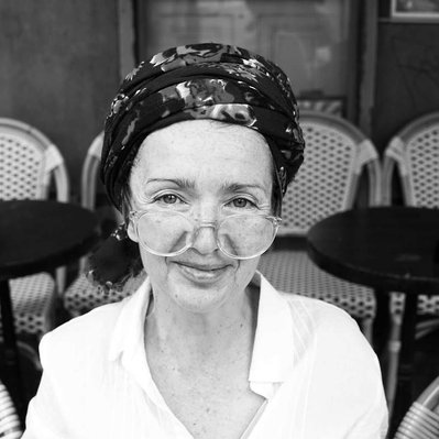 Black and white street photography of the french street photographer David Décamps representing a portrait of a woman with a scarf in her hair and glasses on her nose in Paris.