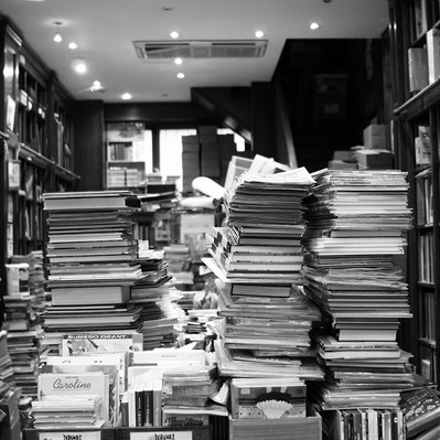Black and white street photography of the french street photographer David Décamps representing a hand with the middle finger up in a book store in Paris.