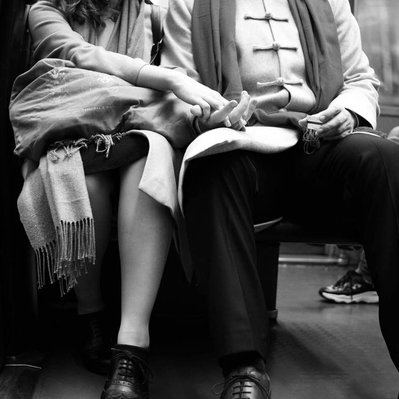 Black and white street photography of the french street photographer David Décamps representing a woman holding the hand of her lover in the subway in Paris.