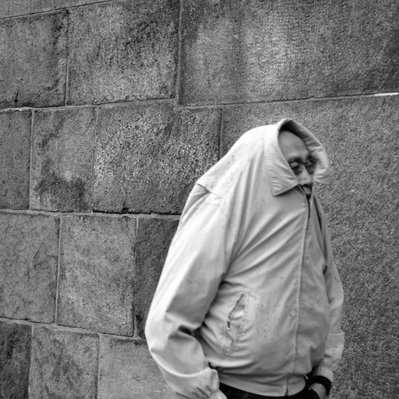 Black and white street photography of the french street photographer David Décamps representing a man hidding under his coat like a turtle in Copenhagen.