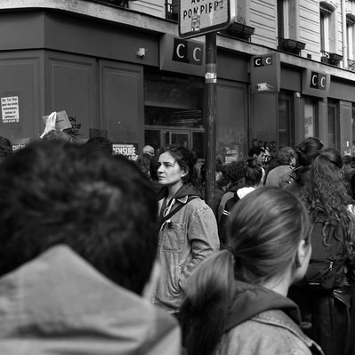 Black and white street photography of the french street photographer David Décamps representing a young woman with her lost mind in the middle of a crowd during a strike in Paris.