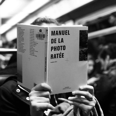 Black and white street photography of the french street photographer David Décamps representing a woman reading a manual of the bad photo in Paris.