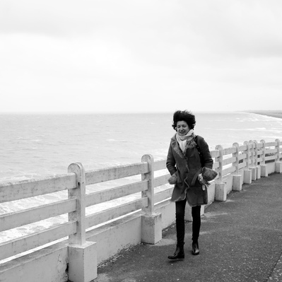 Black and white street photography of the french street photographer David Décamps representing a woman with her hair up because of the wind near the sea.