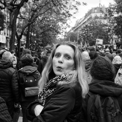 Black and white street photography of the french street photographer David Décamps representing a woman with a surprise face during a strike in Paris.