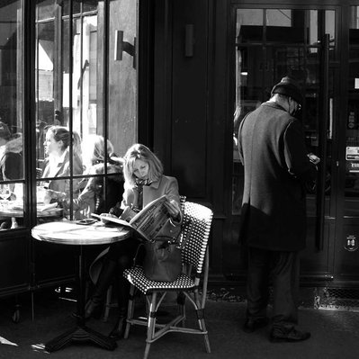 Black and white street photography of the french street photographer David Décamps representing a woman reading her newspaper like a spy in Paris.