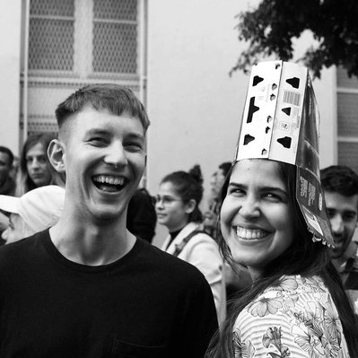 Black and white street photography of the french street photographer David Décamps representing two young people and a girl with a beer hat in Paris.