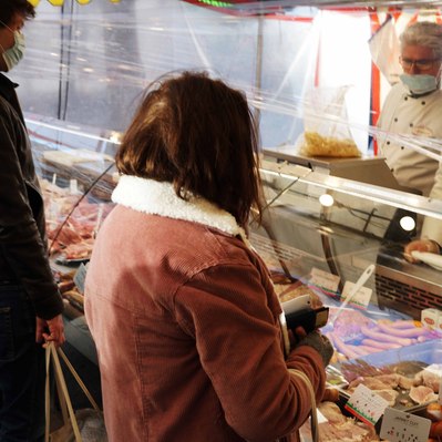 Street photography in colors of the french street photographer David Décamps representing a woman buying some meats in a market in Paris.