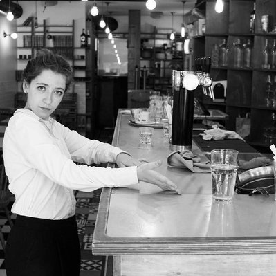 Black and white street photography of the french street photographer David Décamps representing a waitress at the bar in Paris.