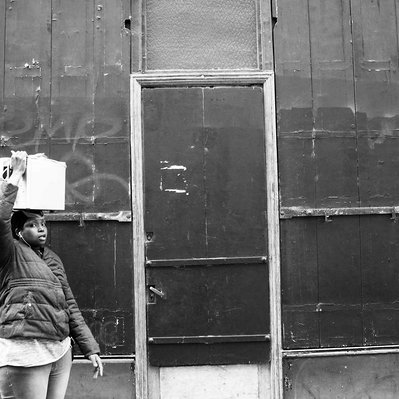 Black and white street photography of the french street photographer David Décamps representing a woman with a package on her head in Paris.
