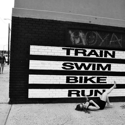 Black and white street photography of the french street photographer David Décamps representing a woman imitating a bike in New York City, USA.