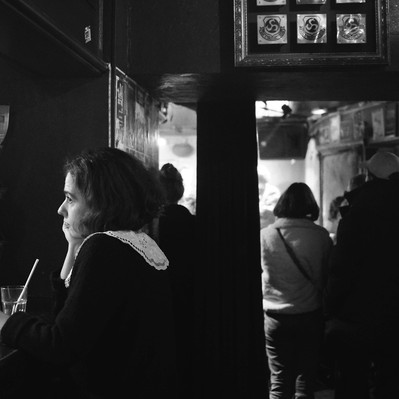 Black and white street photography of the french street photographer David Décamps representing a woman alone and sad in a bar in Paris.