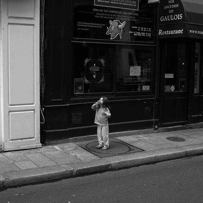 Black and white street photography of the french street photographer David Décamps representing a little girl alone eating a cake in Paris.