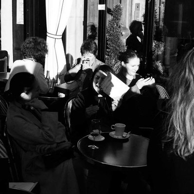 Black and white street photography of the french street photographer David Décamps representing the shadow of the face in the menu of the restaurant in Paris.