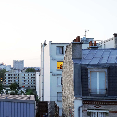 Street photography in colors of  the french street photographer David Décamps representing the view of a woman at her lighted window in Paris.