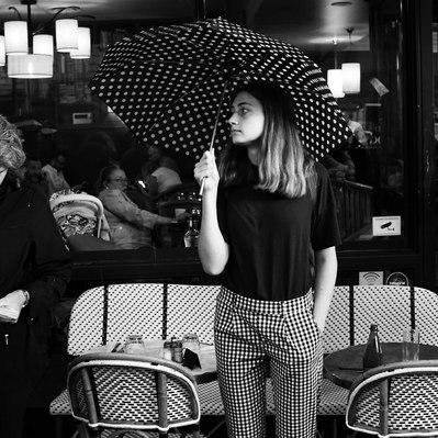 Black and white street photography of the french street photographer David Décamps representing a girl with spotty clothes in a bar in Paris.